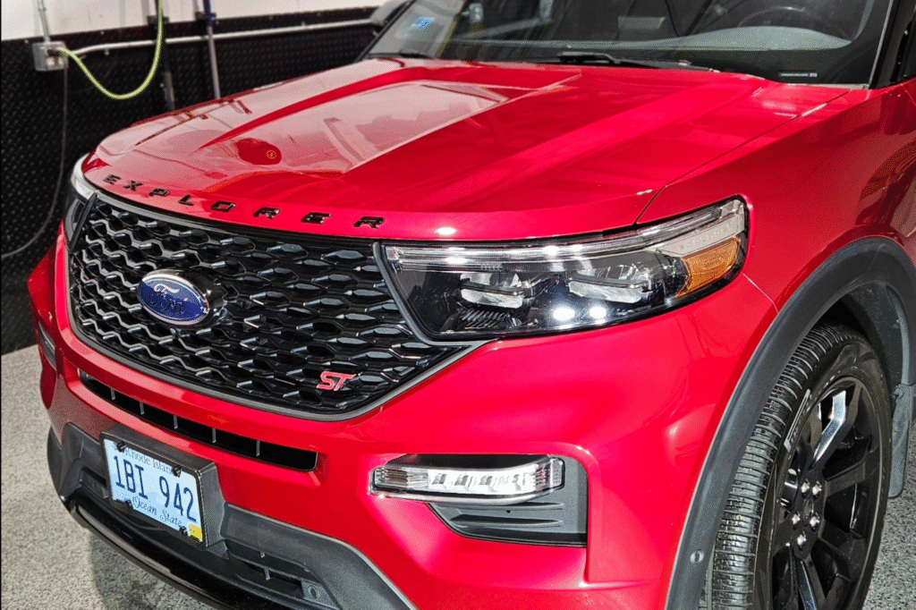 Close-up of a red Ford Explorer's front grill and headlights, showcasing its bold design.