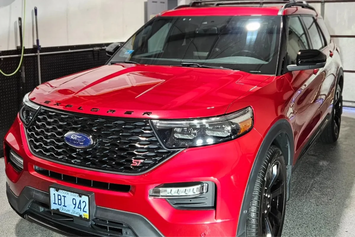 Front view of a red Ford Explorer with a sleek grill and headlights in a well-lit garage