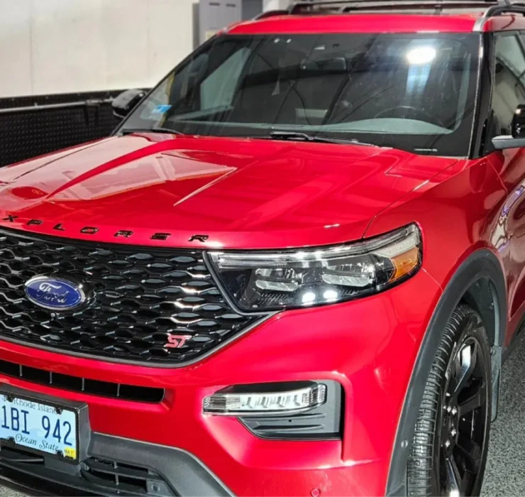 Front view of a red Ford Explorer with a sleek grill and headlights in a well-lit garage