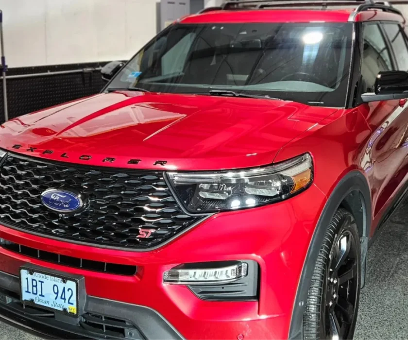Front view of a red Ford Explorer with a sleek grill and headlights in a well-lit garage
