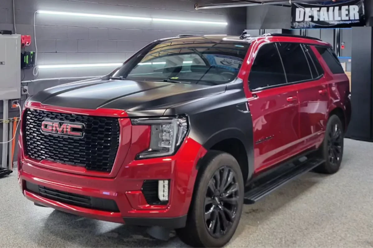 Red GMC SUV featuring a black vinyl wrap in a detailing shop.