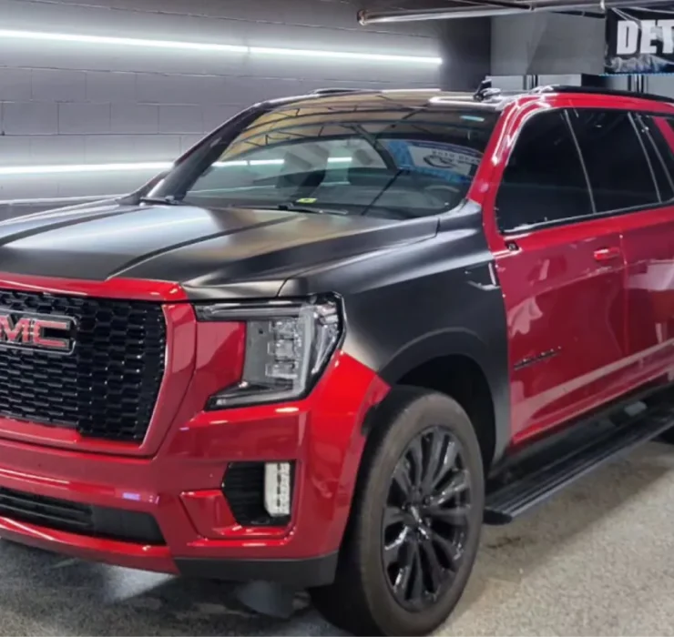 Red GMC SUV featuring a black vinyl wrap in a detailing shop.
