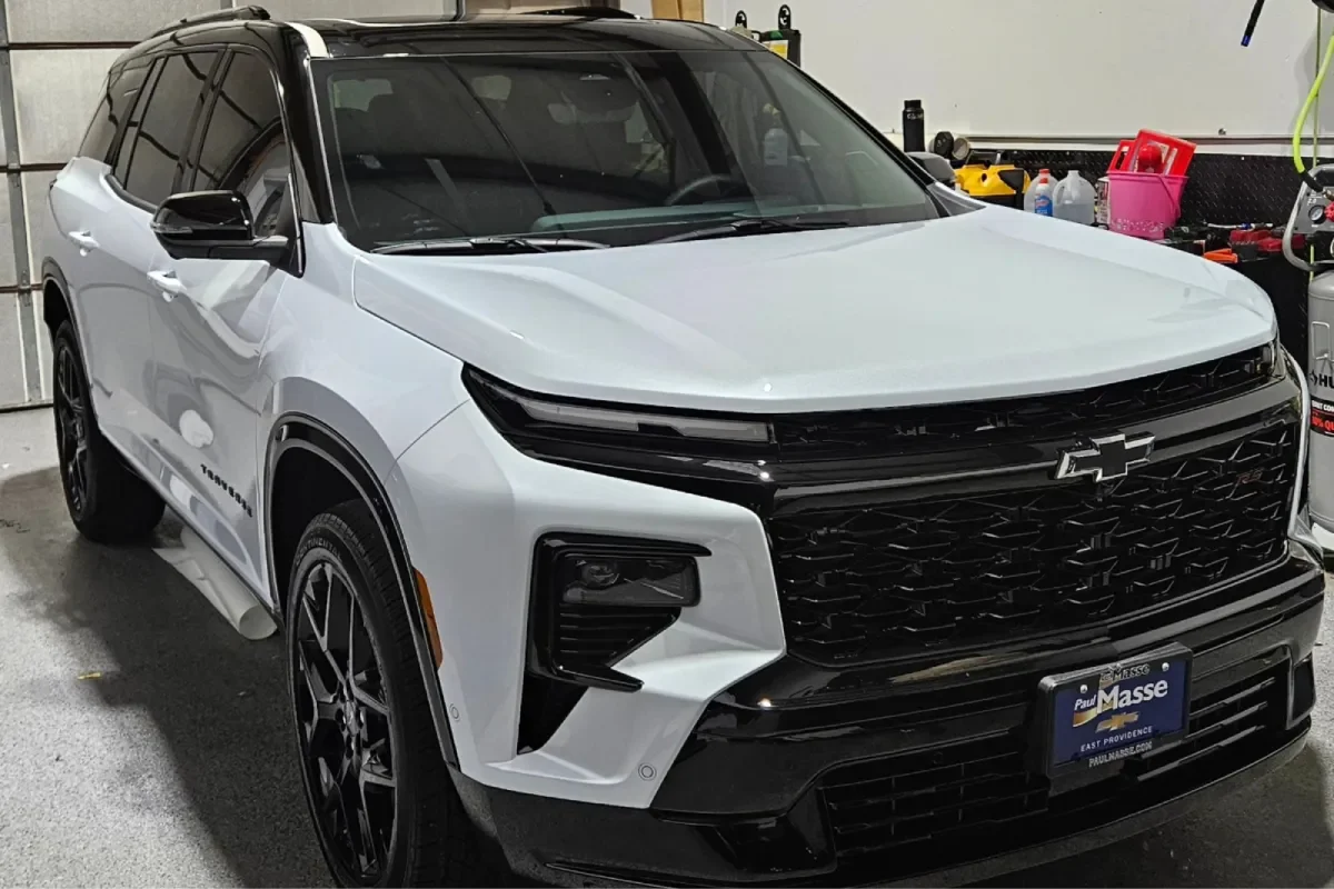 A white Chevrolet Traverse RS parked in a garage with a black grille and tinted windows.