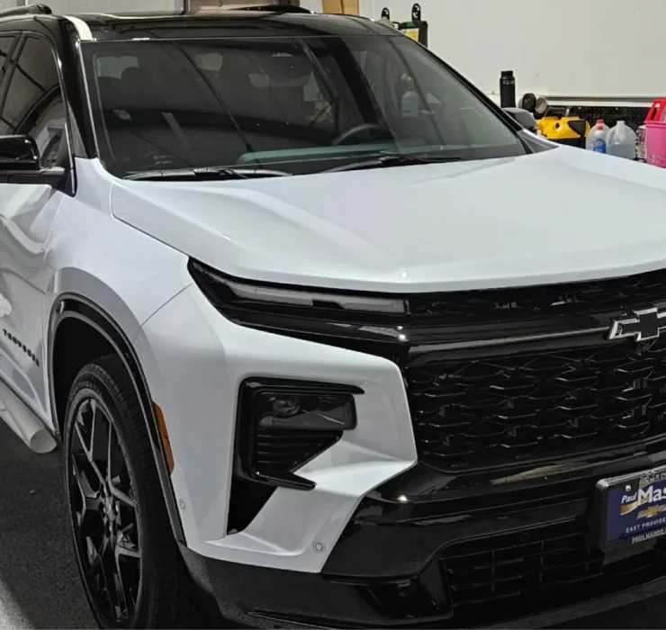 A white Chevrolet Traverse RS parked in a garage with a black grille and tinted windows.